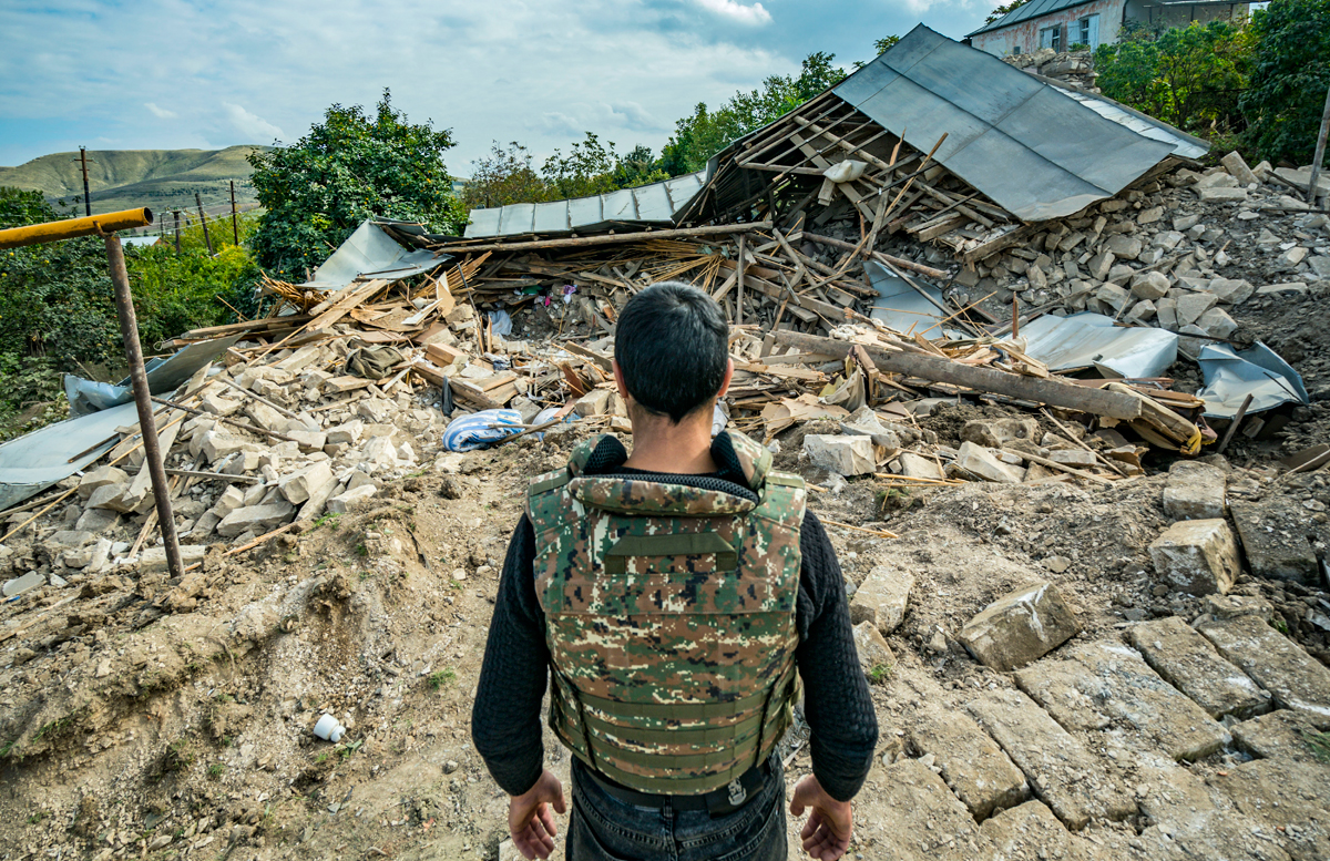 Солдат осматривает руины разрушенного дома в селе Мартуни от взрыва азербайджанской ракеты. 11 октября 2020