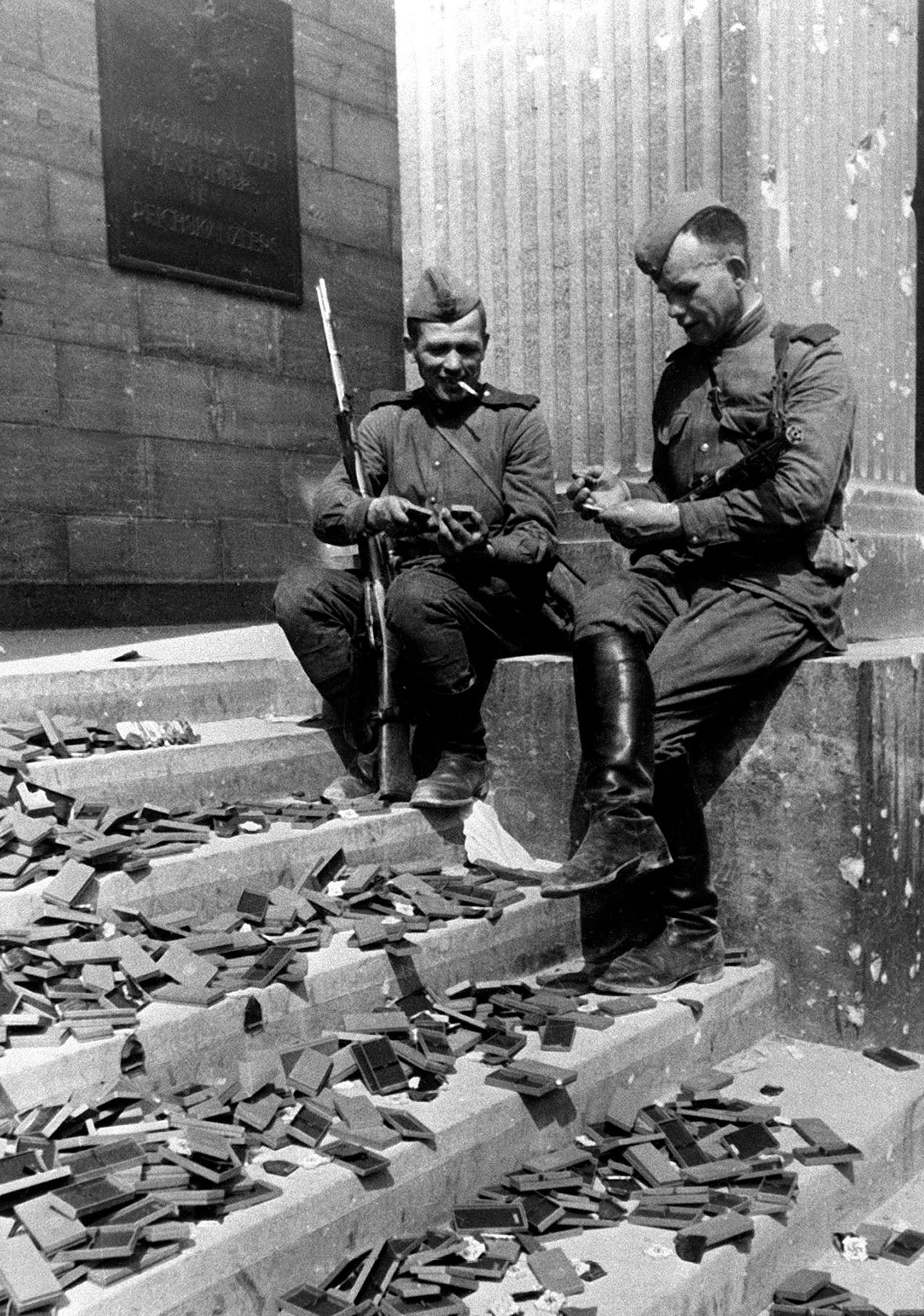 Бойцы Красной армии на ступенях здания Рейхсканцелярии после взятия города советскими войсками рассматривают брошенные награды гитлеровской армии