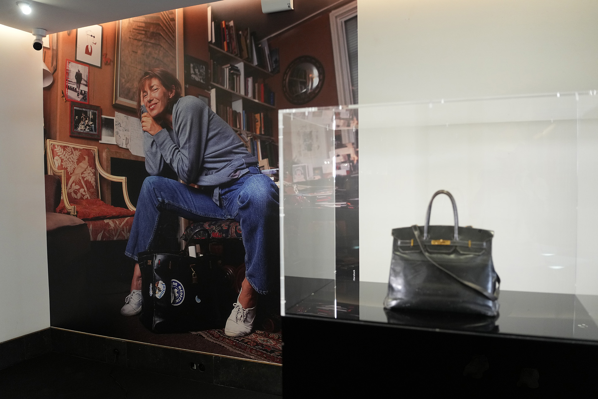 Оригинальная черная кожаная сумка Джейн Биркин Hermès Birkin на фоне фотопортрета самой Джейн