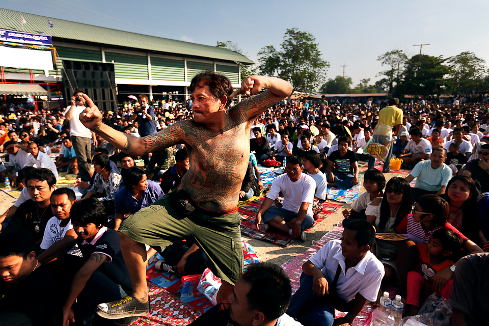 Каждый год в начале марта в Таиланде проходит так называемый День почитания мастера — Вай Кру. Это что-то среднее между фестивалем, симпозиумом и огромным тату-салоном. Происходит все в монастыре Банг Пхра, недалеко от Бангкока. Когда-то его настоятелем был легендарный монах Луанг Пхор Пын, один из самых мистических персонажей Таиланда в XX веке. Если коротко, то все тайцы безоговорочно верили в то, что аджан Пын был магом. Он лечил любые болезни, амулеты, которые он делал, до сих пор считаются самыми сильными, но главное, конечно, сак янт. По эффективности магии татуировок сравниться с ним не мог в Таиланде никто. Аджан Пын умер 10 лет назад. Но он по-прежнему здесь. Как это часто бывает со святыми людьми, после смерти он не стал разлагаться, а просто засох. Теперь лежит здесь, в красивом стеклянном гробу. И каждый, кто приходит сюда, просто обязан засвидетельствовать свое почтение.