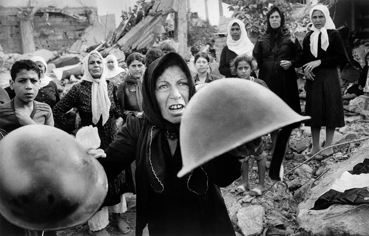 Этот кадр американский фотожурналист Билл Фоли сделал в сентябре 1982 года в столице Ливана Бейруте. Палестинка размахивает шлемами во время поминок по жертвам массовых убийств в лагере для палестинских беженцев в Сабре. Она считает, что такие шлемы носили те, кто убивали ее соотечественников.
Резню в лагере для беженцев устроили ливанские боевики во время гражданской войны в Ливане и Ливано-израильской войны 1982 года. В погоне за палестинскими боевиками они убили, по разным оценкам, до полутора тысяч человек, в том числе женщин и детей.